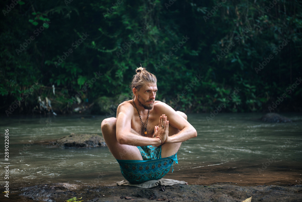 Yoga practice and meditation in nature. Man practicing near river Yoga practice and meditation in nature. Man practicing near river