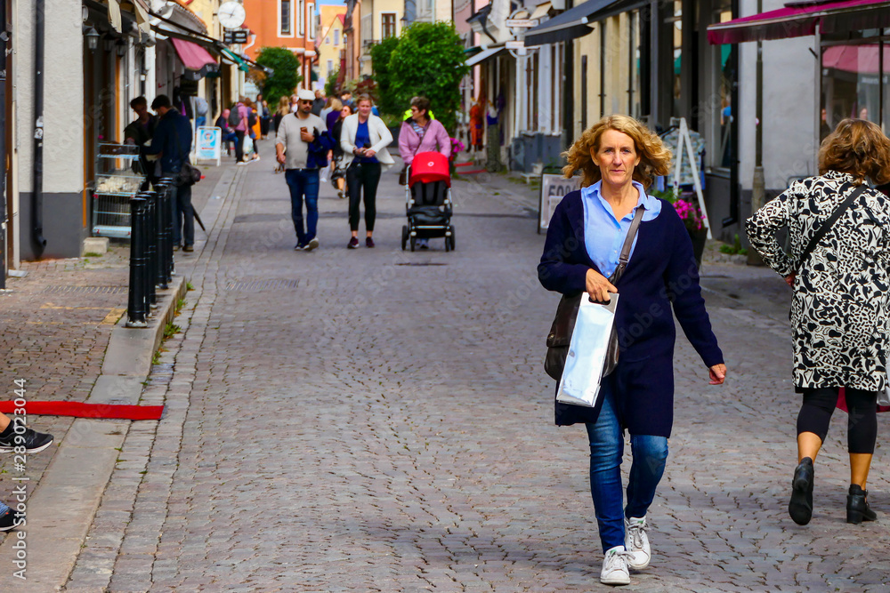 Φωτογραφία Visby, Gotland, Sweden A woman walks  on the main shopping street, Adelsgatan