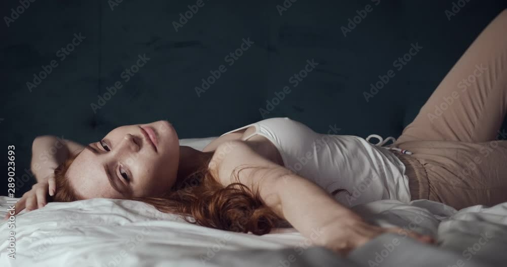 Young redheaded woman in home clothes lying on the bed. Young redheaded woman in home clothes lying on the bed.