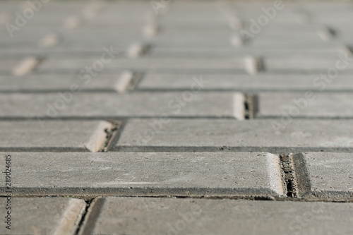 Outdoor gray paving stones with shallow depth of field. Close up blurred texture abstract background