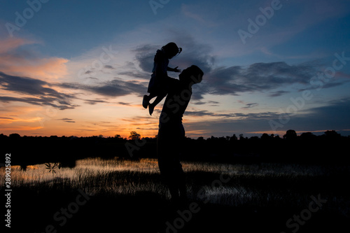 Silhouette man throws up girl field in the evening. Concept to build relationships within the family.