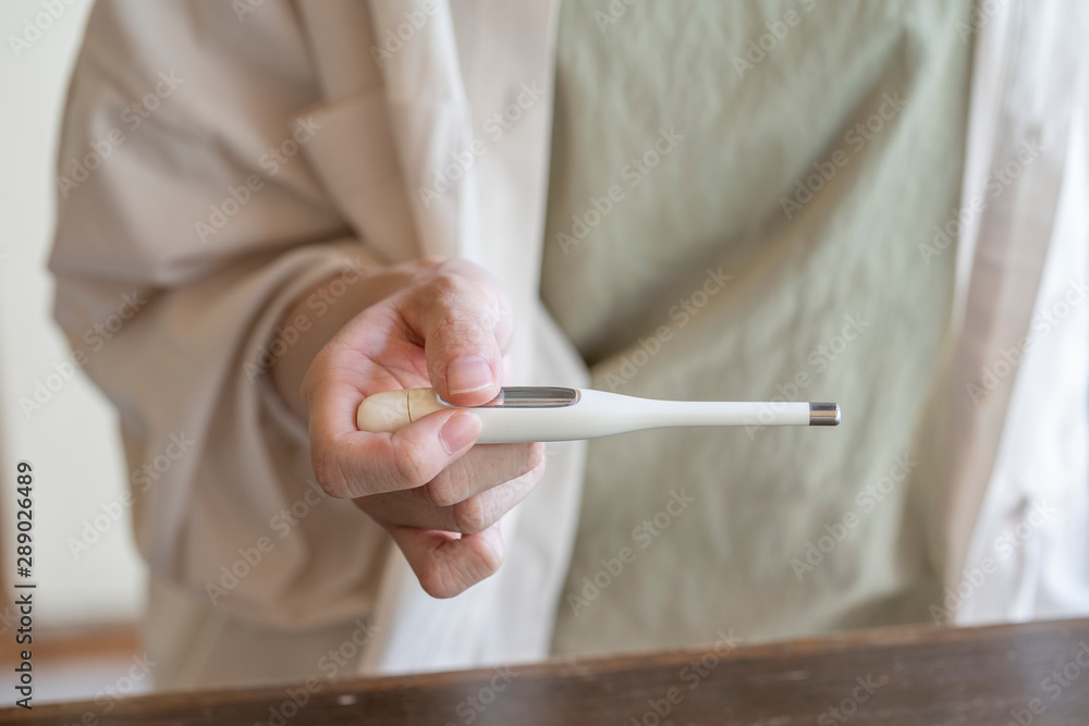 体温計で熱を測る女性の手元 体温計で熱を測る女性の手元