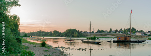 Tableau sur toile wooden riverboats ona calm Loire River at sunset in the French countryside near