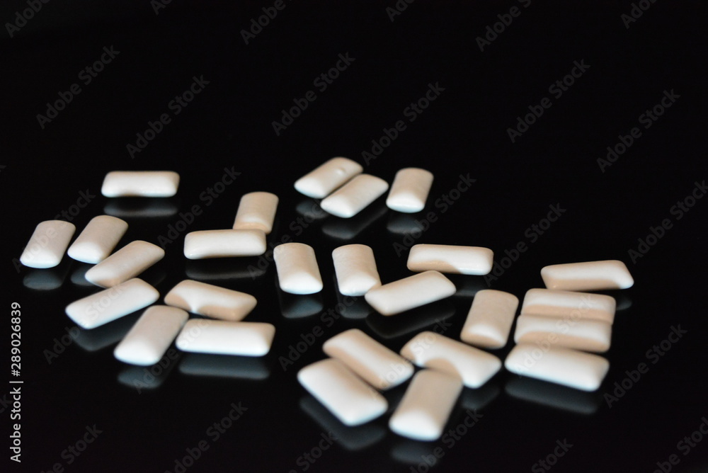 White delicious pillows, chewing gum pillows located on a black glossy surface. White delicious pillows, chewing gum pillows located on a black glossy surface.