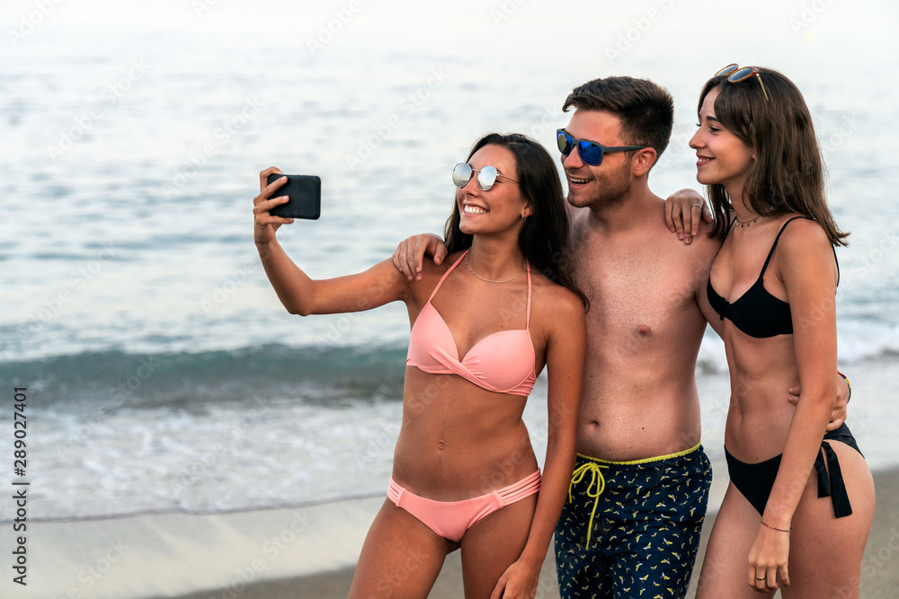 Young friends taking selfie on ocean seashore beach together