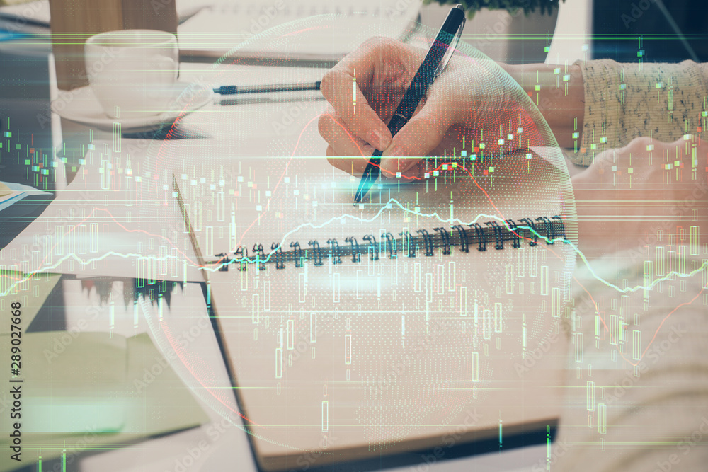 Forex chart hologram on hand taking notes background. Concept of analysis. Double exposure Forex chart hologram on hand taking notes background. Concept of analysis. Double exposure