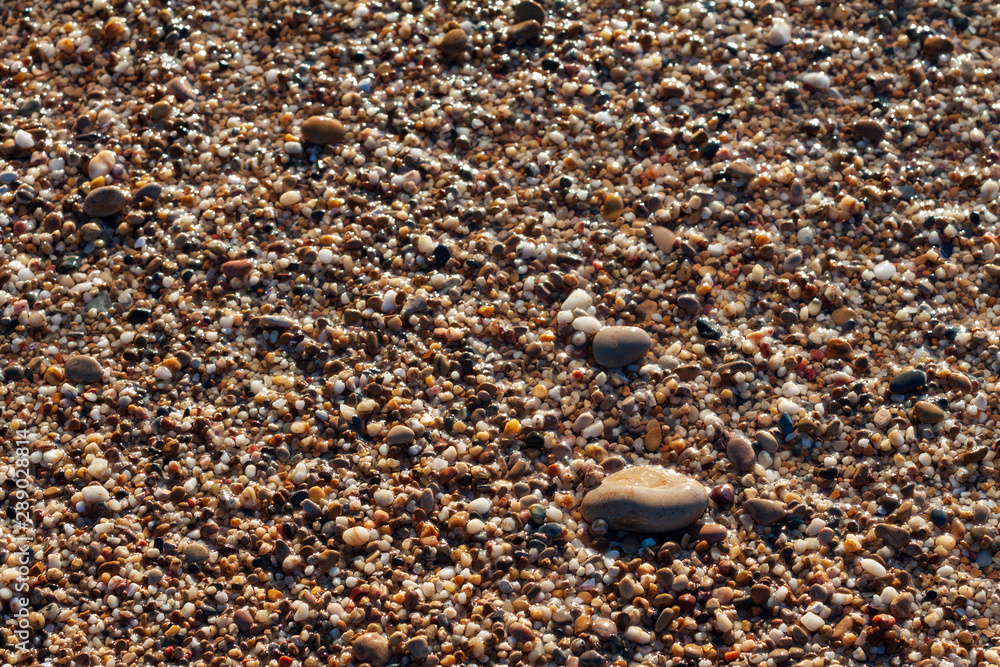 sea pebbles colored granite on the beach background stones. The shore of the beach with sand and pebbles washed by the waves of the sea. sea pebbles colored granite on the beach background stones. The shore of the beach with sand and pebbles washed by the waves of the sea.