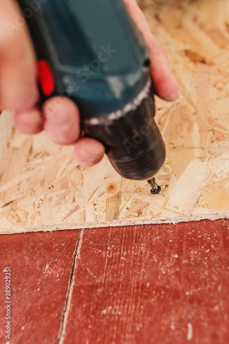 Close-up work of a screwdriver on installing an osb plate with self-tapping screws