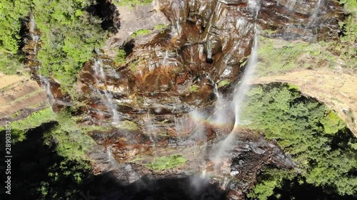 Wentworth Falls huge cliff waterfall with rainbow in New South Wales, Australia, aerial drone shot descending photo