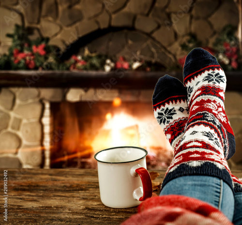 Woman legs with christmas socks and fireplace 