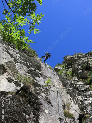 alpiniste en descente en rappel avec corde dans une paroi en montagne après l'escalade
