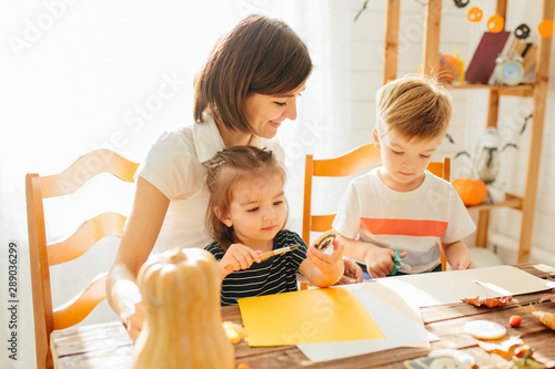 family mother and child daughter in hat witch are preparing for Halloween carve a pumpkin and decorate the house Happy Halloween concept