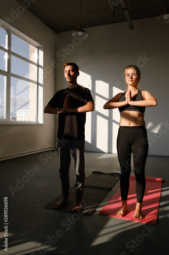 Man and women holding hands in namaste gesture, ready to start practicing yoga meditation exercises at group training class 
