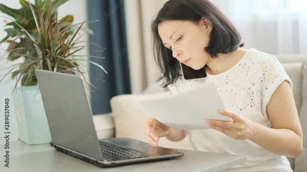 slow motion. Female multi-tasking at work place. Businesswoman working in office talking over cell phone, checking a financial report and using laptop. slow motion. Female multi-tasking at work place. Businesswoman working in office talking over cell phone, checking a financial report and using laptop.