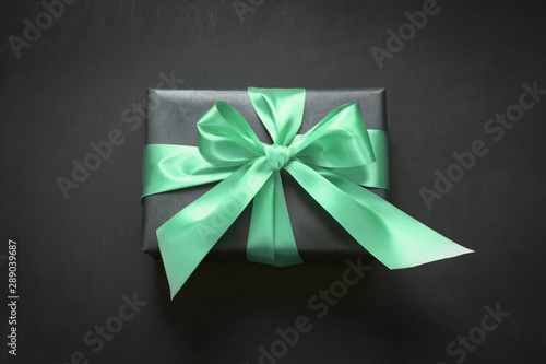 Gift box wrapped in black paper with neo mint ribbon on black surface. Top view. Color of the 2020 year.