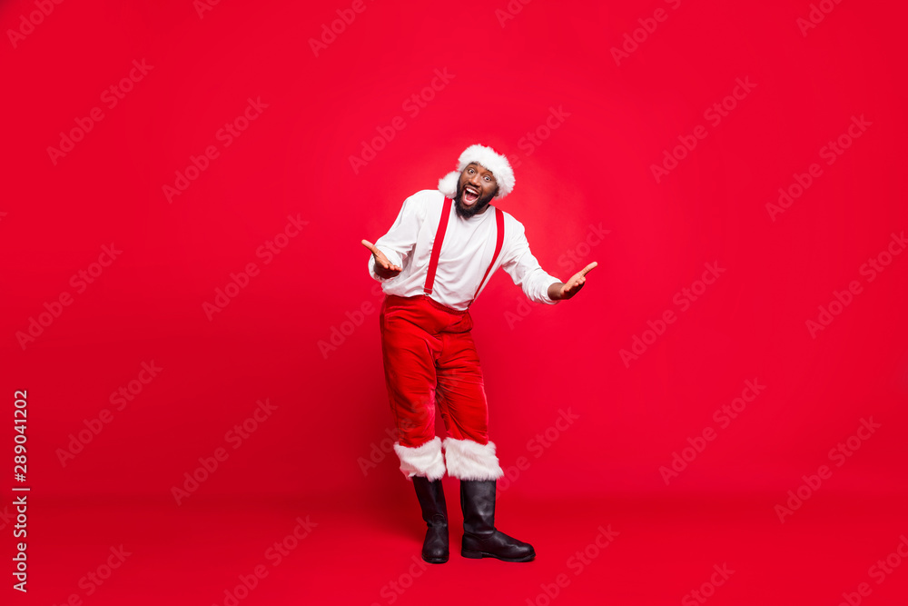 Full length photo of funky hipster afro american santa having xmas cap screaming wearing pants trousers isolated over red background Full length photo of funky hipster afro american santa having xmas cap screaming wearing pants trousers isolated over red background
