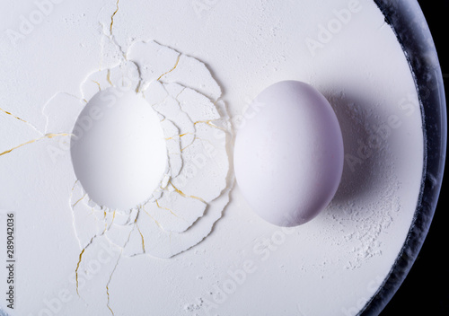 An egg lying on white plaster or starch. Cracks and surface texture. The texture of white gypsum with a microrelief of different shapes. White or light gray kitchen background. photo