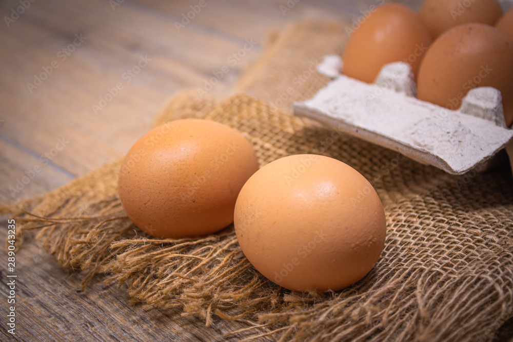 uova con contenitore di cartone su juta e tavolo di legno uova con contenitore di cartone su juta e tavolo di legno