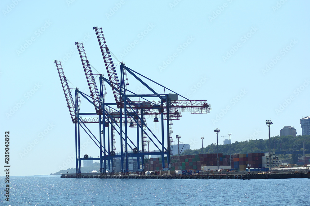 Industrial view of sea port warehouse, container spreaders and gantry cranes. Import export, global logistics concept.