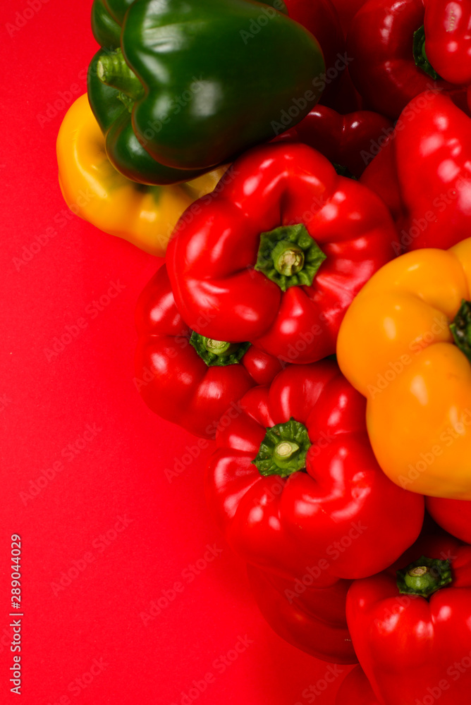 Fresh red, yelow, green bell pepper on a red background. Fresh red, yelow, green bell pepper on a red background.