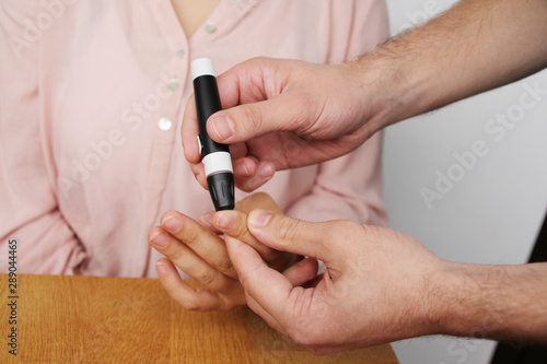 doctor holds in both hands a glucometer for measuring blood sugar and teaches a young girl to make a finger test, medical concept, diabetic, close-up, copy space
