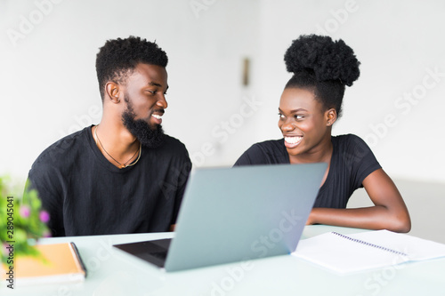 Young african man and woman working on laptop in business office