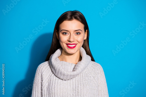 Close up photo of gorgeous lady looking at camera smiling wearing grey jumper isolated over blue background