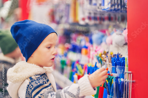boy chooses pens in office supplies store.
