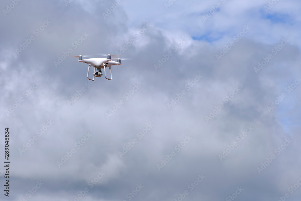 White drone quadcopter flying on the air for take a photo and video with white cloudy background. White drone quadcopter flying on the air for take a photo and video with white cloudy background.