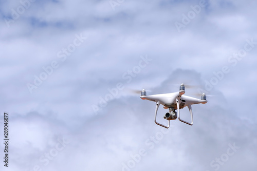 White drone quadcopter flying on the air for take a photo and video with white cloudy background. © 168 Studio