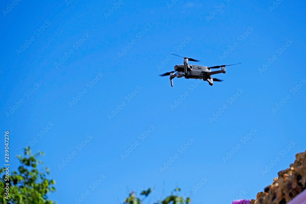 Black drone quadcopter flying on the air for take a photo and video with blue sky background. Black drone quadcopter flying on the air for take a photo and video with blue sky background.