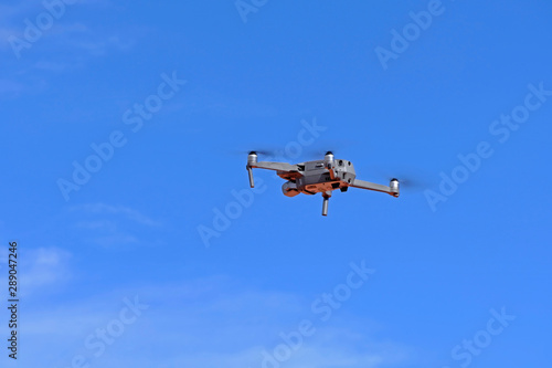 Black drone quadcopter flying on the air for take a photo and video with blue sky background.