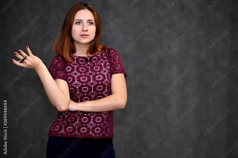 Portrait of a brunette girl with beautiful brown hair in a purple t-shirt on a gray background. He stands in different poses, demonstrates emotions. Portrait of a brunette girl with beautiful brown hair in a purple t-shirt on a gray background. He stands in different poses, demonstrates emotions.