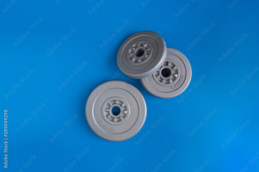 three gray plastic dumbbell pancakes on the color surface three gray plastic dumbbell pancakes on the color surface