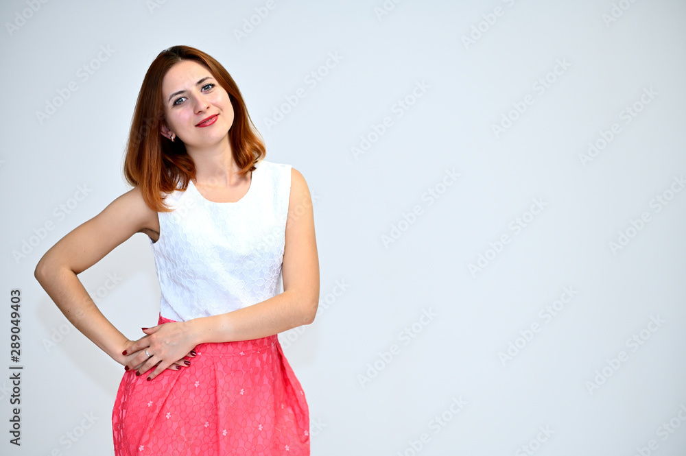 Portrait of a brunette girl with beautiful brown hair in a pink and white dress on a white background. He stands in different poses, demonstrates emotions. Portrait of a brunette girl with beautiful brown hair in a pink and white dress on a white background. He stands in different poses, demonstrates emotions.
