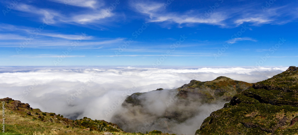 Wide angle shot of Mountain peaks in the clouds against blue sky from Pico Ruivo and Pico do Arieiro, beautiful mountain landscape, central Madeira, Portugal