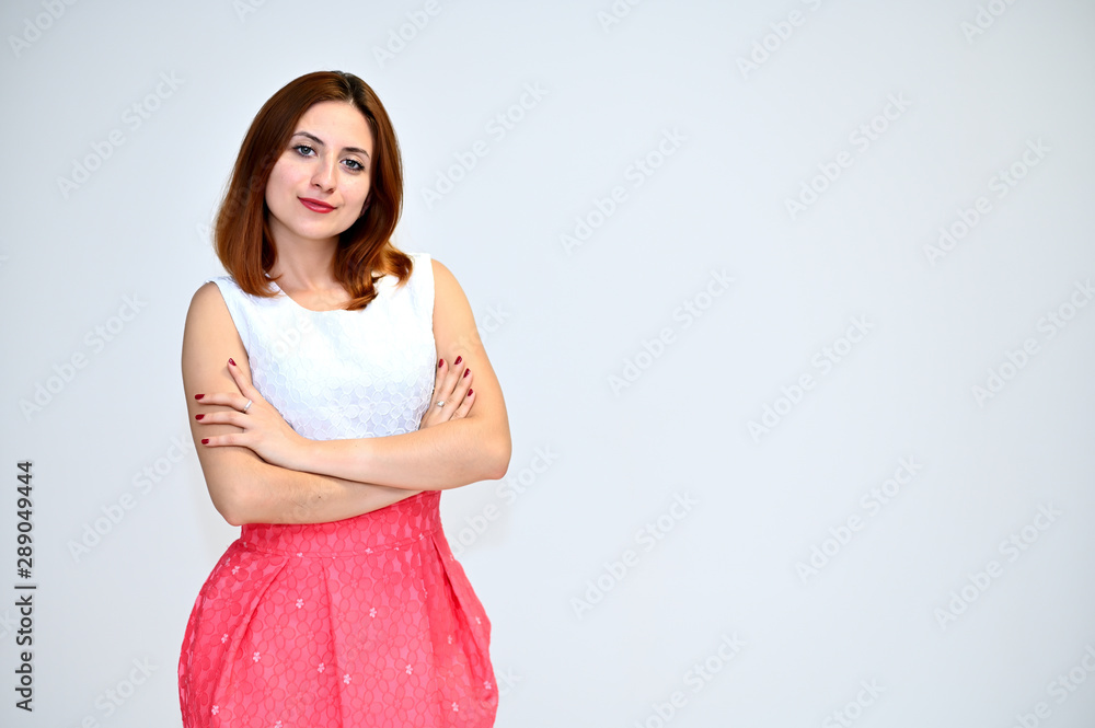 Portrait of a brunette girl with beautiful brown hair in a pink and white dress on a white background. He stands in different poses, demonstrates emotions. Portrait of a brunette girl with beautiful brown hair in a pink and white dress on a white background. He stands in different poses, demonstrates emotions.