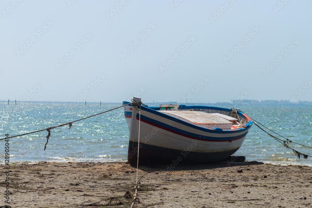 Blue, white and red boat on the seashore Blue, white and red boat on the seashore