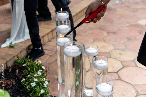 Various heights of water tubes hold outdoor floating candle decorations for the party are being lit as night time comes. photo