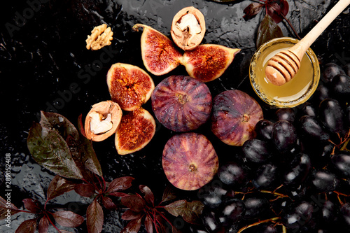Autumn frame background. Autumn food still life with season fruits grape and figs, honey on a black table. Thanksgiving day. © bondarillia