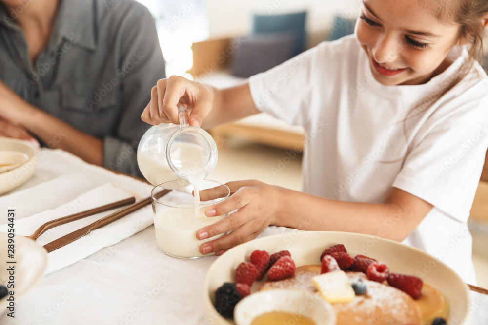 Image of beautiful family mother and little daughter having breakfast at home in morning Image of beautiful family mother and little daughter having breakfast at home in morning