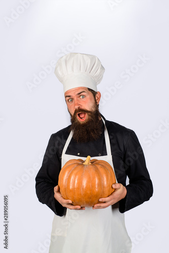 Harvest pumpkin. Fresh Pumpkin. Bearded cook in chef hat with pumpkin. Diet food. Healthy vegetarian eating. Farm market. Big pumpkin for Halloween. Autumn vegetables. Chef preparing meal in kitchen.