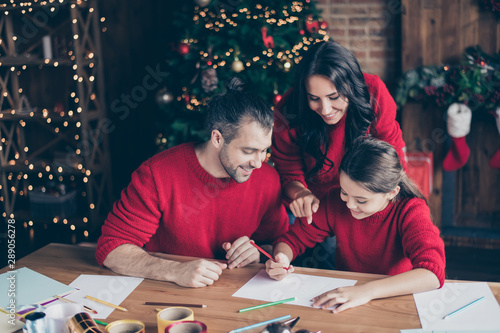 Photo of nice cheerful comfort kind friendly people with parents wearing red pullovers helping their school schoolgirl daughter write wish list for sants claus
