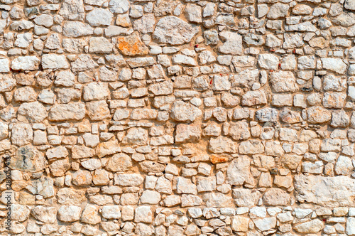 An old time damaged wall made of rough stone. Natural background for design.