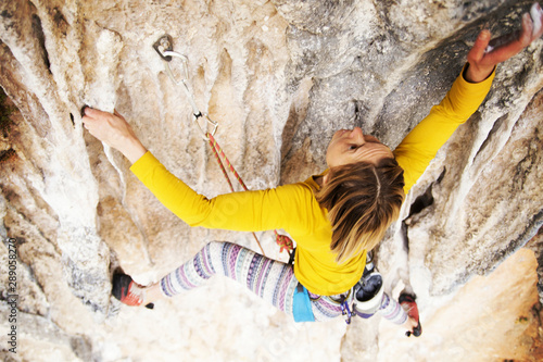 Fototapeta Naklejka Na Ścianę i Meble -  Climber overcomes challenging climbing route. A girl climbs a rock. Woman engaged in extreme sport. Extreme hobby.