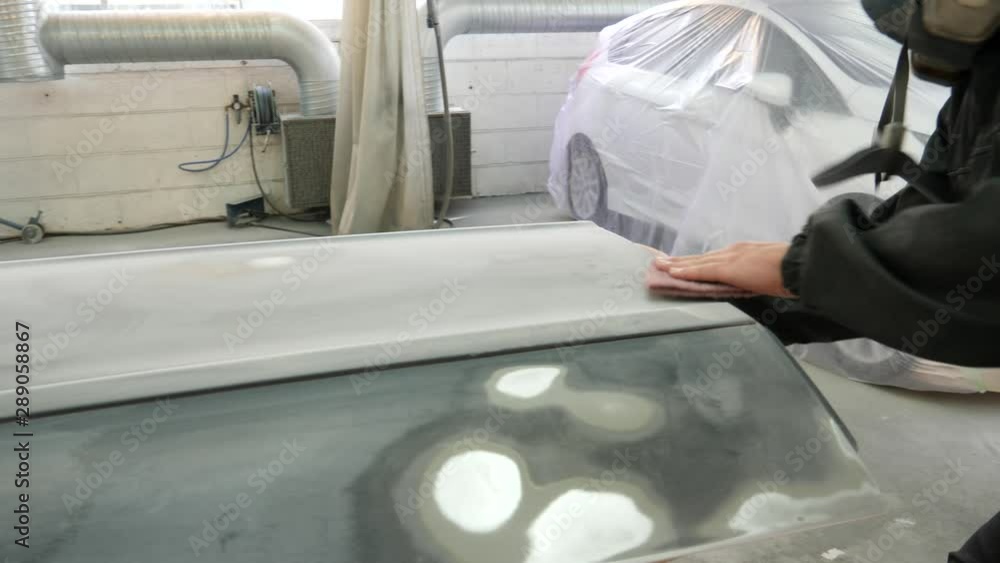 Autobody technician hand sanding a car door in preparation for painting Autobody technician hand sanding a car door in preparation for painting