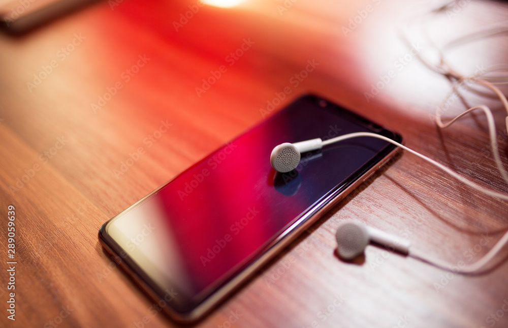 Smartphone with earphones on wooden table Smartphone with earphones on wooden table