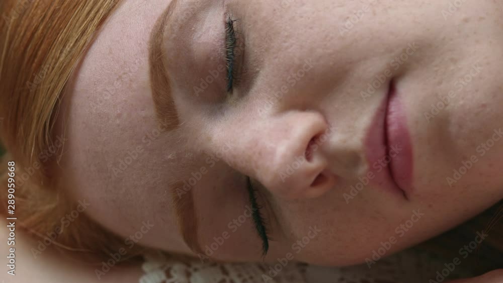 Macro close up: Young beautiful red haired girl is smiling directly at the camera. Slow Motion Shot Macro close up: Young beautiful red haired girl is smiling directly at the camera. Slow Motion Shot