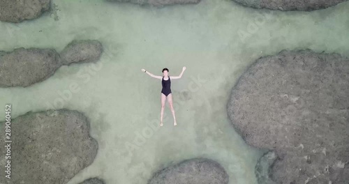 Beautiful Young Girl Floating in a Relaxed Pose in Ocean Near a Reef. Static View. photo