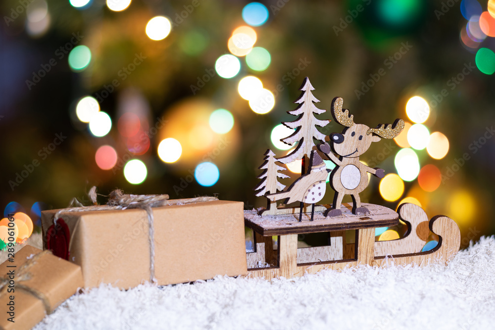 New Year and Christmas background for greetings, banner, postcard, advertisement with place for text. Deer on a sled and boxes with gifts close-up on a bokeh background. Copy space, front view.